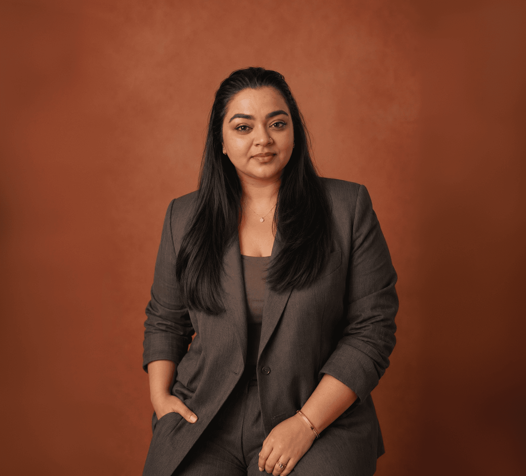 Tripti KRV, creative director, portrait against a warm terracotta backdrop