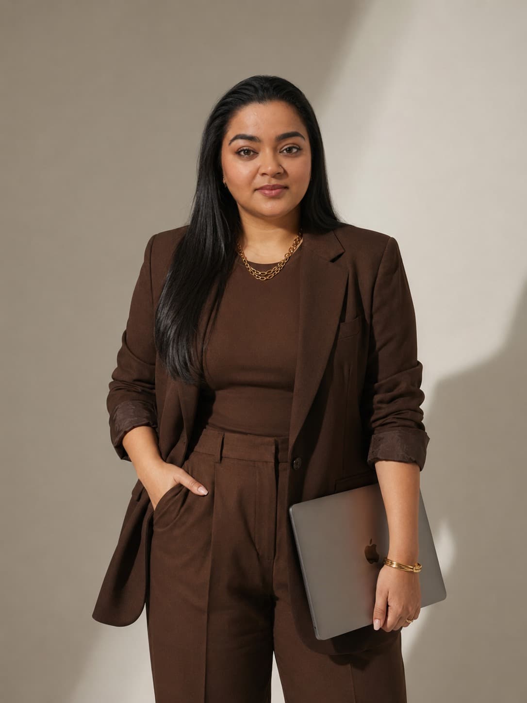 Tripti KRV, creative director, wearing a brown blazer and holding a laptop